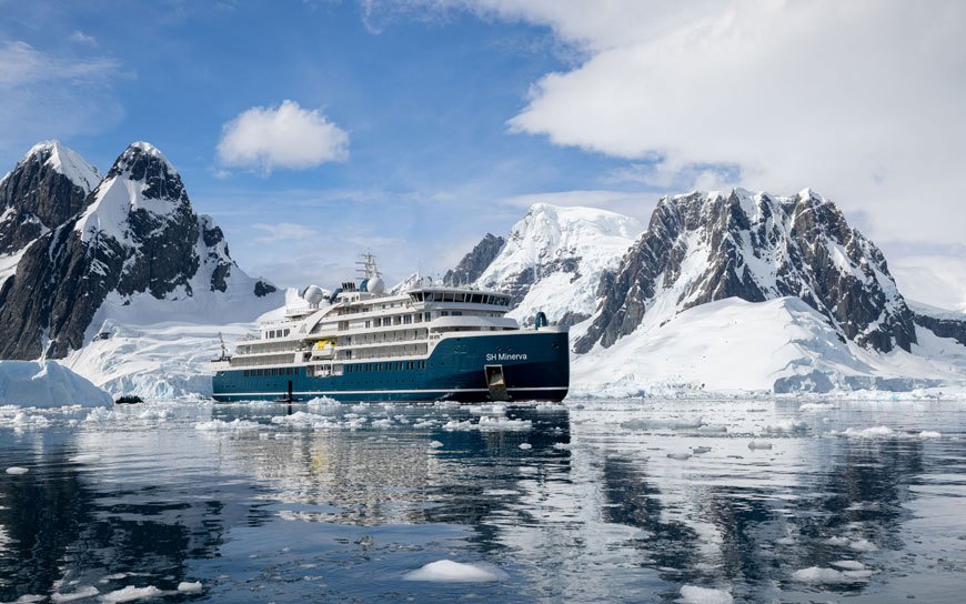 Navio de cruzeiro de expedição entre montanhas cobertas de neve na Antártida